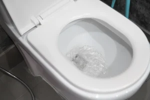 Ein Spülrandloses WC in einem dunkel gefliesten Bad. Die Spülung wurde gerade betätigt.