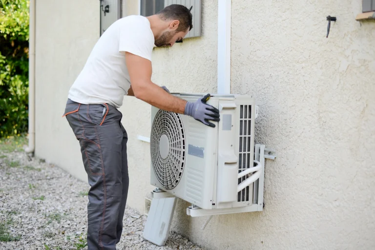 Ein Installateur montiert eine Klimaanlage an einer Aluminium-Halterung.