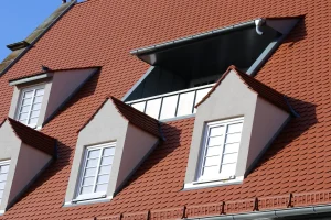 Rotes Ziegeldach mit drei Giebelgauben, einer Flachdachgaube und einer zentralen Dachloggia.