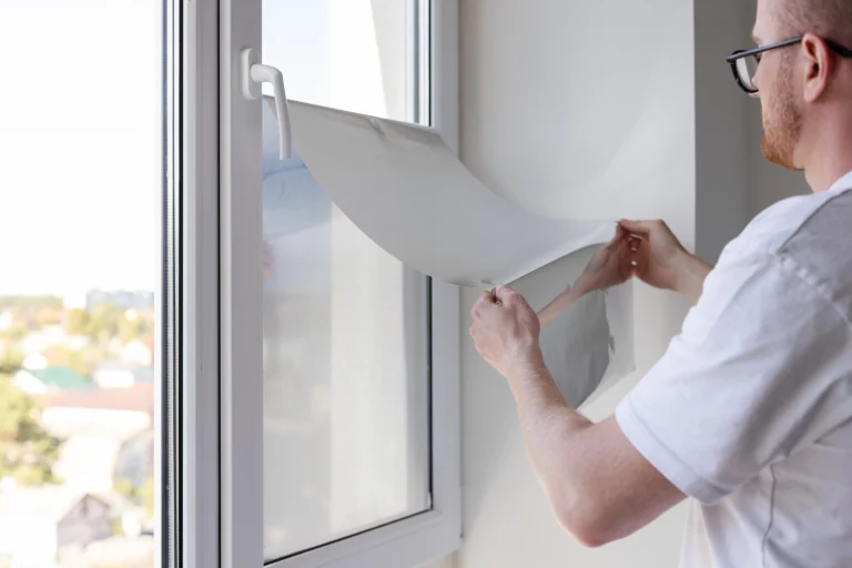 Ein Mann bringt eine Fensterfolie an einem Fenster an.