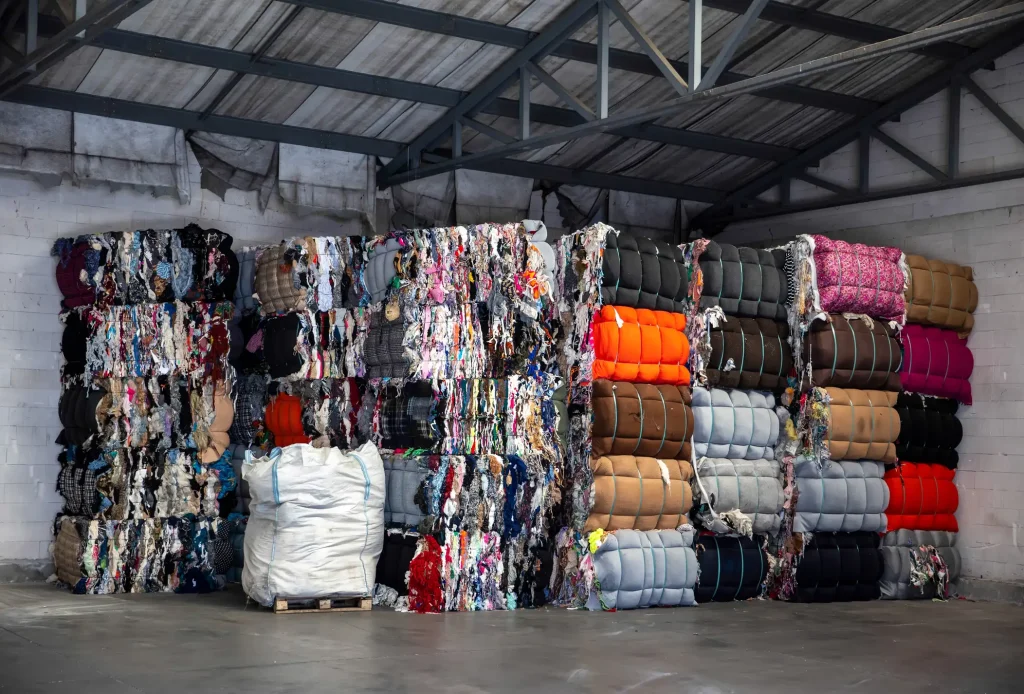 Gepresste Textilballen und Altkleider in einer Halle für Textilrecycling und Entsorgung.