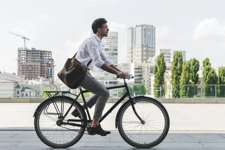 Ein Mann fährt auf einem Fahrrad vor einer Skyline einer Stadt.