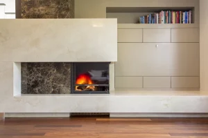 Modernes Kamin-Element mit Marmorverkleidung und brennendem Feuer, integriert neben grauen Schränken und einem Bücherregal.
