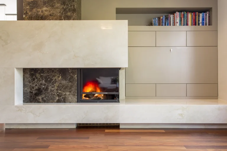 Modernes Kamin-Element mit Marmorverkleidung und brennendem Feuer, integriert neben grauen Schränken und einem Bücherregal.