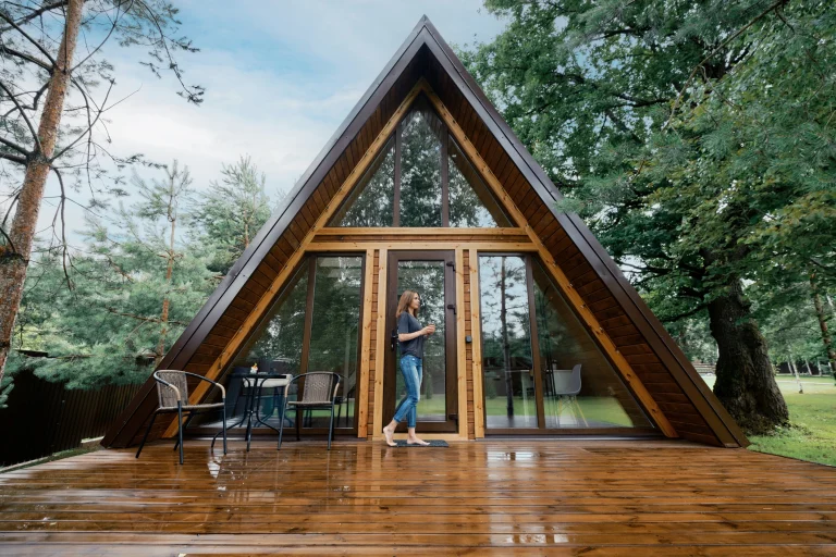Moderner Nurdachhaus-Holzbau mit großer Glasfront und Holzterrasse im Grünen.