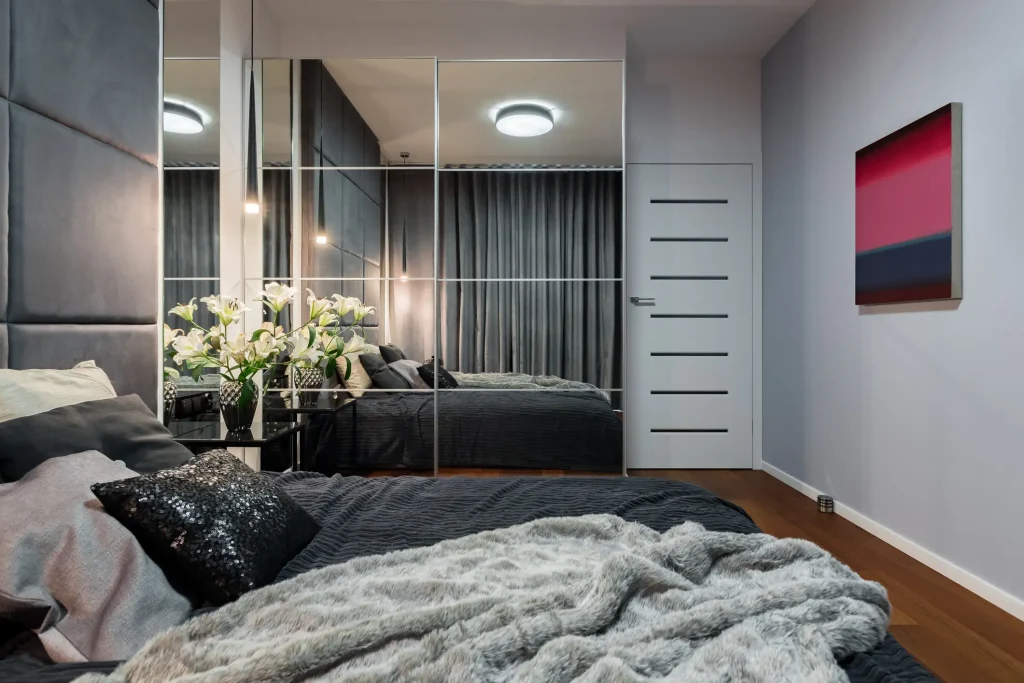 Großer Spiegelschrank mit Schiebetüren und integrierten Kassettenfeldern in einem modernen Schlafzimmer.