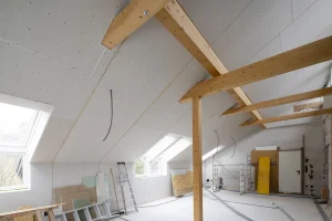 Dachgeschossausbau mit verkleideten Dachschrägen aus Gipskarton und freiliegenden Holzbalken.