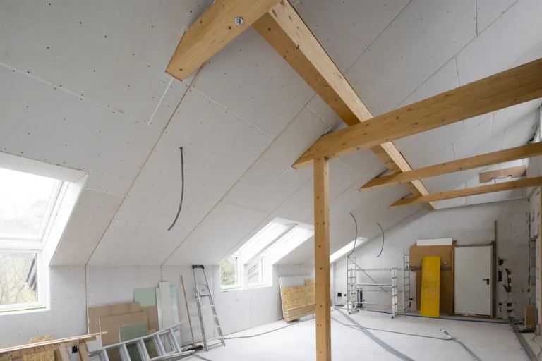 Dachgeschossausbau mit verkleideten Dachschrägen aus Gipskarton und freiliegenden Holzbalken.