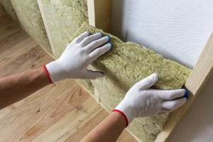 Einsetzen einer Mineralwolle-Dämmplatte in eine Wand aus Holzständerwerk.