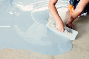 Handwerker trägt Epoxidharz auf den Boden auf.