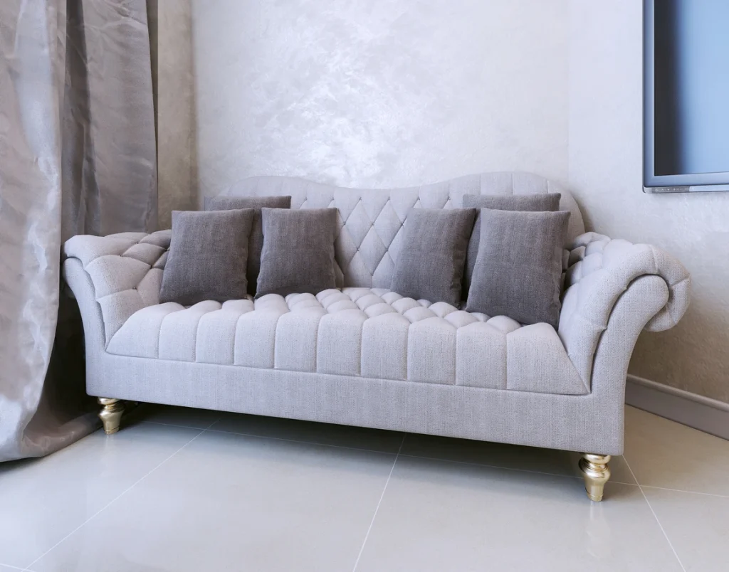 Helles Stoffsofa mit grauen Kissen vor einer makellos glatt verspachtelten Wand.