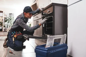Techniker führt eine Backofen-Reparatur durch und prüft den Innenraum des Einbauherds in der Küche.