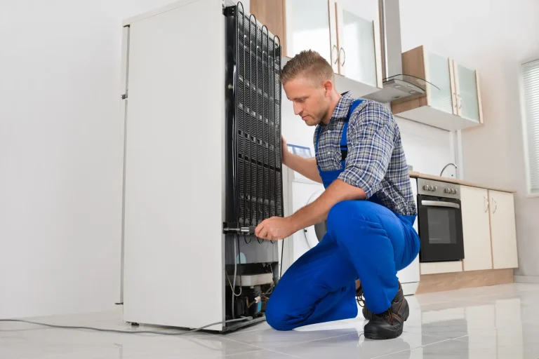Techniker führt eine Kühlschrank-Reparatur an den Kühl-Verflüssigerlamellen auf der Rückseite durch.