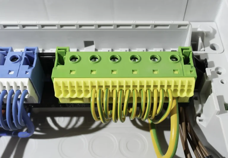 Nahaufnahme eines Schutzleiter-Klemmblocks mit angeschlossenen grün-gelben Erdungsleitern in einem Elektroverteiler.