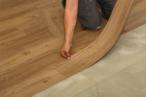 Bodenleger verlegt biegsame PVC-Planken in Holzoptik auf verklebtem Untergrund.