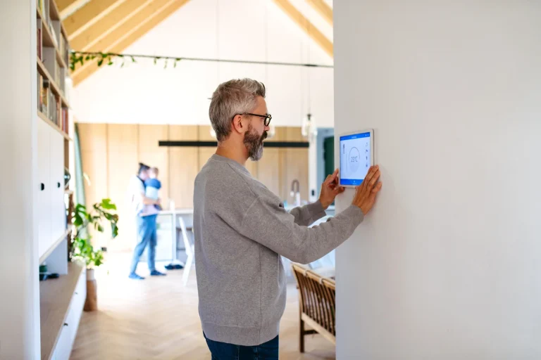Mann benutzt an der Wand installiertes Smart-Home Bedienfeld.