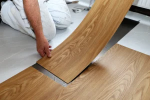 Handwerker verlegt Vinylbodenplatten.
