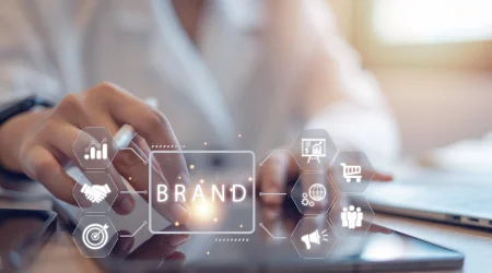 Eine Frau arbeitet auf ihrem Tablet, darüber befindet sich eine Grafik, die die 3 Säulen der Corporate Identity (CI) abbildet.