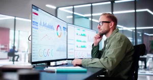 Ein Datenanalyst sitzt am Schreibtisch und analysiert Daten seiner Firma.