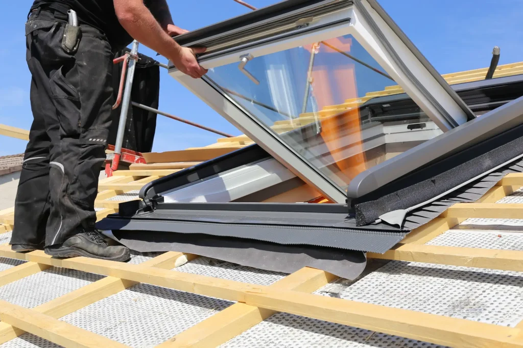 Handwerker bei der Montage eines Dachfensters auf einer vorbereiteten Dachkonstruktion.