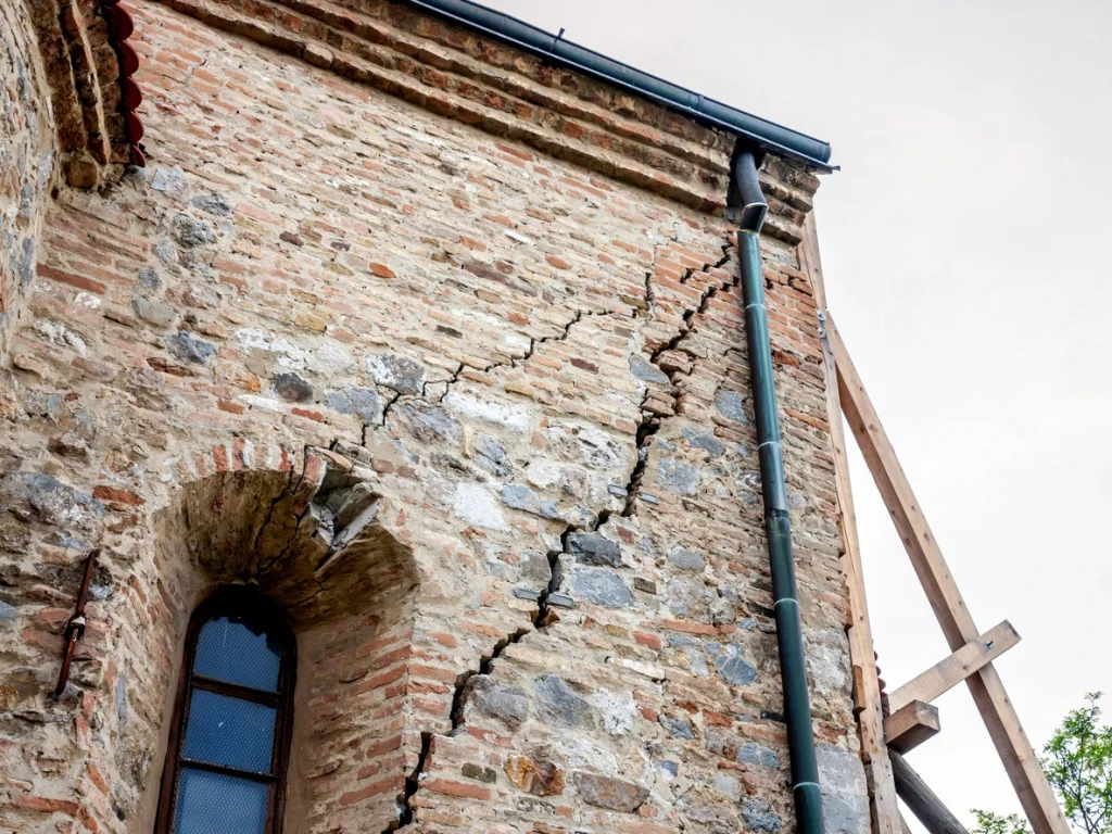 Rissige Steinmauer-Fassade eines alten und stark verfallenden Gebäudes mit Verwitterungsspuren