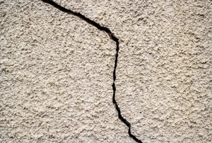 Großer Riss in der Außenwand eines Hauses als Zeichen für Bauschaden oder Setzungsprobleme.
