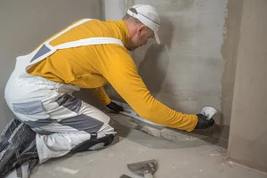 Handwerker bringt eine Horizontalsperre gegen aufsteigende Feuchtigkeit in einer Wand an, um Mauerwerk vor Nässe zu schützen.
