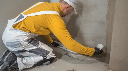 Handwerker bringt eine Horizontalsperre gegen aufsteigende Feuchtigkeit in einer Wand an, um Mauerwerk vor Nässe zu schützen.