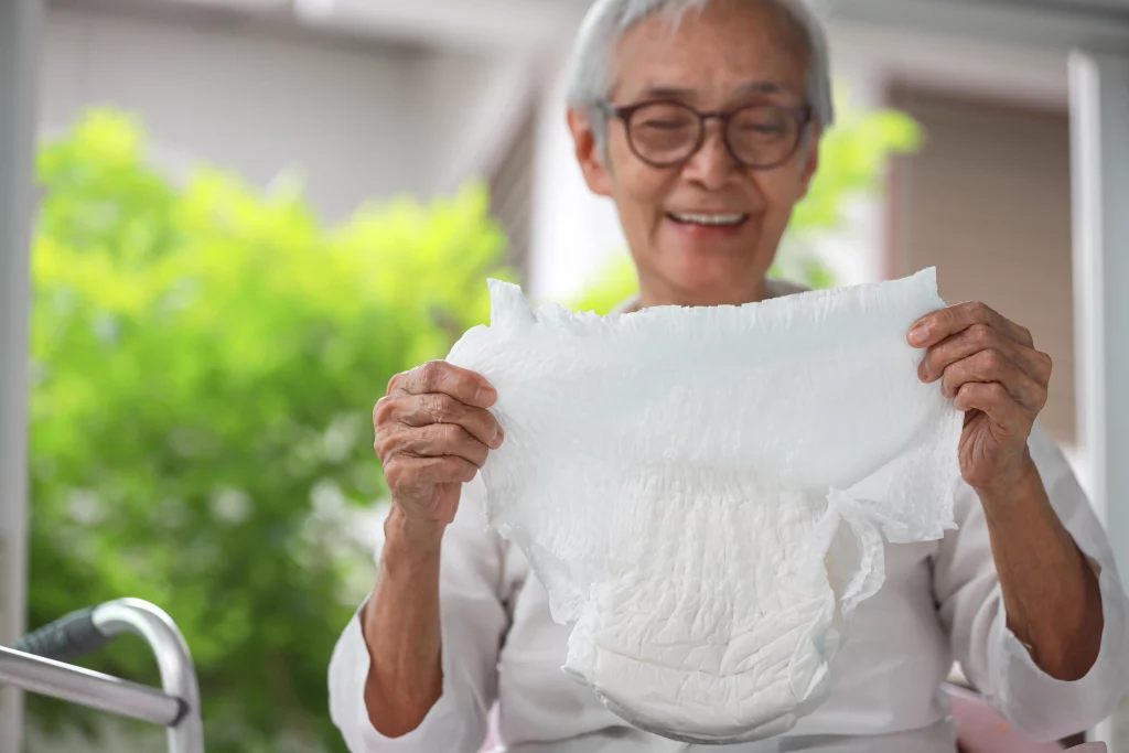 Ältere asiatische Frau mit einer Windel als Hilfsmittel gegen Inkontinenz