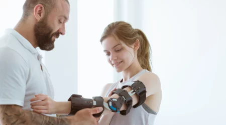 Physiotherapeut legt einer jungen Frau eine Armorthese an