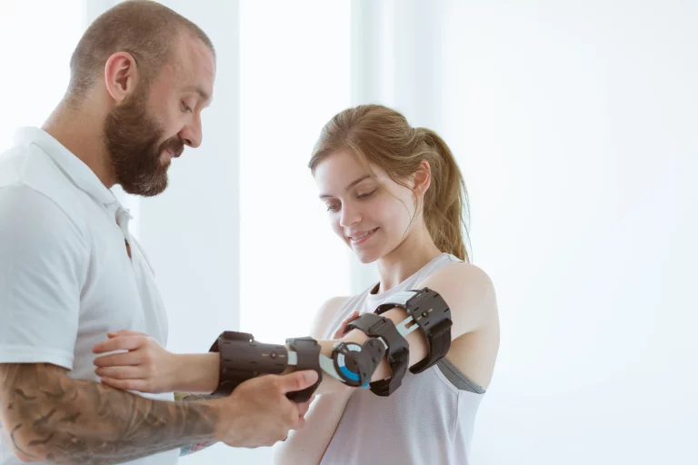 Physiotherapeut legt einer jungen Frau eine Armorthese an