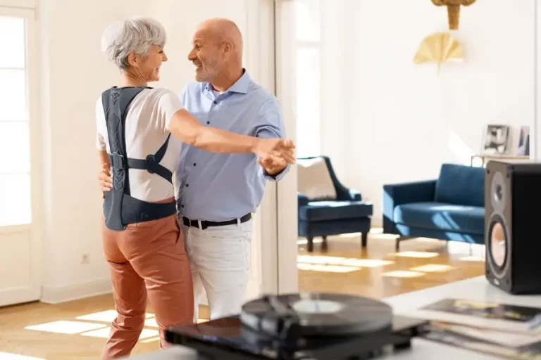 Tanzendes Rentnerpaar, bei der die Frau eine Rückenorthese gegen Osteoporose trägt