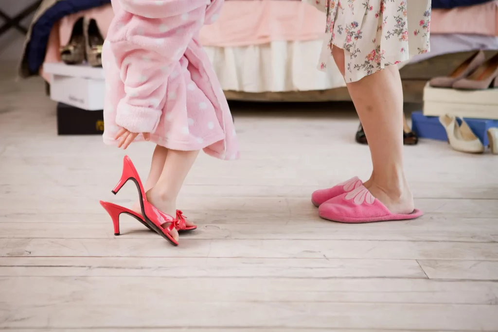 Eine kleine Tochter in pink farbigen High Heels und ihre Mutter in pinken Hausschuhen