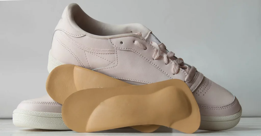 Weiße Sneaker mit orthopädischen Einlagen vor einem weißen Hintergrund