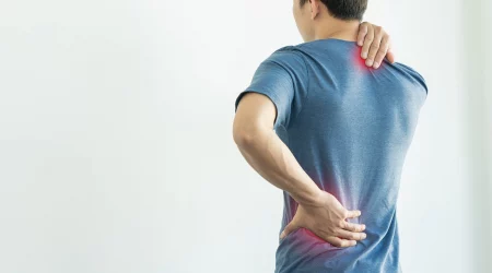 Mann hält sich den Nacken und den Rücken bei Schmerzen