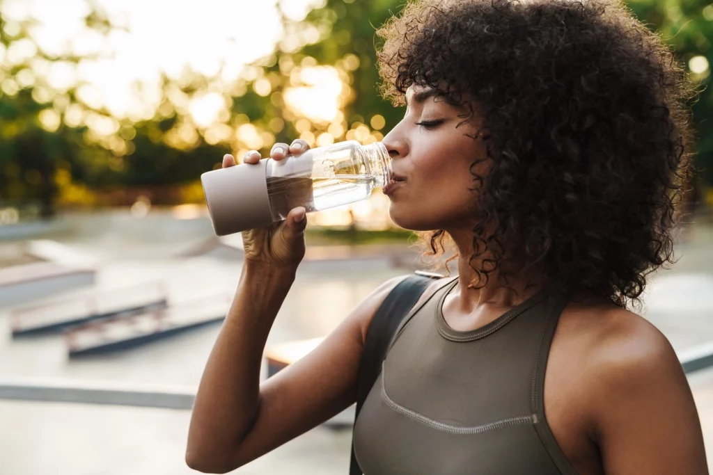 sportliche Frau trinkt aus Wasserflasche