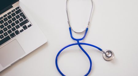 Blaues Stethoskop vor einem Laptop