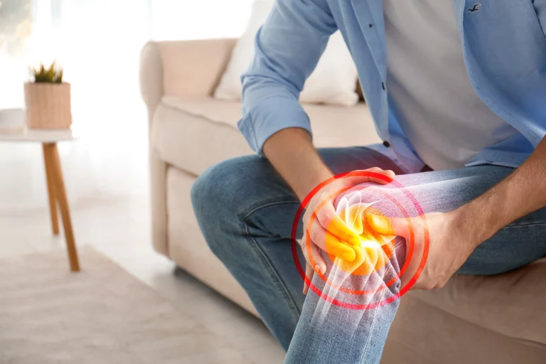 Person hält sich das Knie. Rote Grafik symbolisiert schmerzen im Knie.