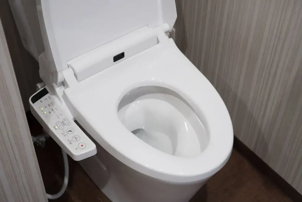 Ein modernes japanisches WC mit integriertem Bidet und elektronischer Steuerung. Die Bedienelemente an der Seite bieten verschiedene Funktionen wie Wasserstrahlintensität und Trocknung, was Komfort und Hygiene im Alter vereinfacht.