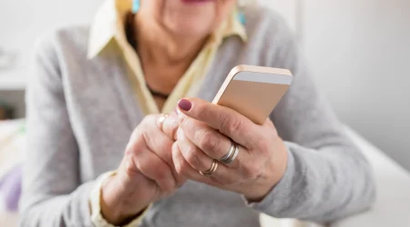 Ältere Dame tippt auf ihrem Smartphone.