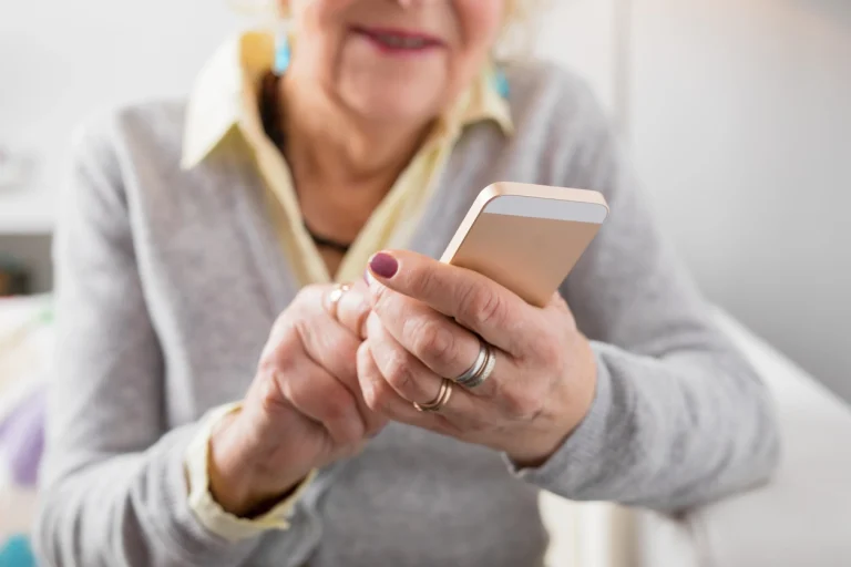 Ältere Dame tippt auf ihrem Smartphone.