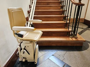 Ein Sitzlift an einer hölzernen Innentreppe mit eleganten Geländern.