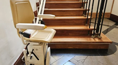 Ein Sitzlift an einer hölzernen Innentreppe mit eleganten Geländern.