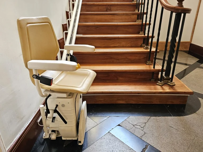 Ein Sitzlift an einer hölzernen Innentreppe mit eleganten Geländern.