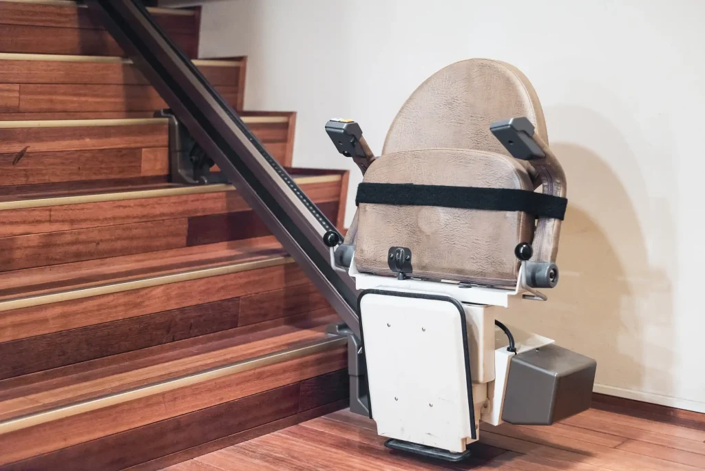 Barrierefreier Treppenlift an einer Holztreppe in einem Innenraum. Das Bild zeigt eine elektrisch betriebene Sitzplattform, die an einer Schiene entlang der Treppe montiert ist.