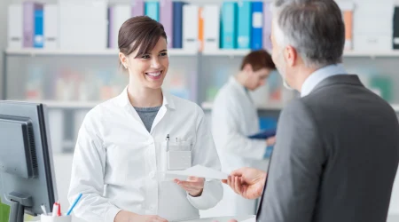 Gesundheitskaufmann übergibt einer jungen Frau ein Formular.