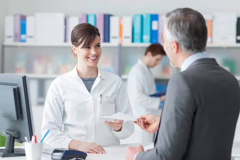Gesundheitskaufmann übergibt einer jungen Frau ein Formular.