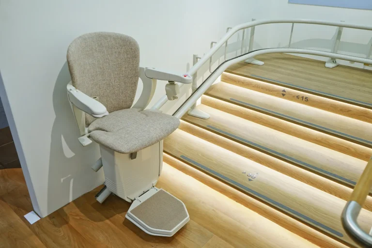 Ein Treppenlift mit gepolstertem Sitz und Armlehnen ist an einer geschwungenen Treppe montiert.