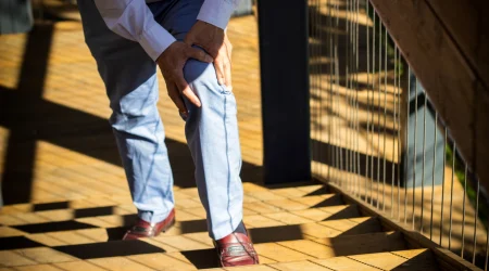 Älterer Mann hält sich das Knie beim Treppensteigen – Symbolbild für eingeschränkte Mobilität und mögliche Hilfe durch einen Stehlift.