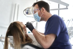 Ein Zahnarzt behandelt eine Patientin. Sie liegt auf einem Behandlungsstuhl.
